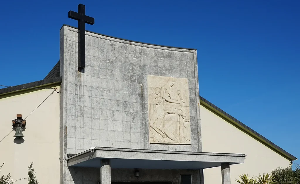 Exterior de capilla en un cementerio con relieve de Cristo y cruz en negro